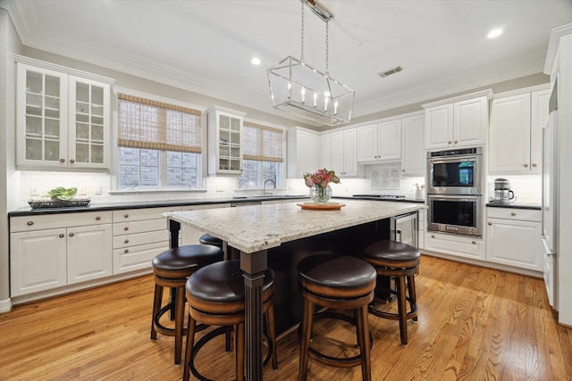333 Sugarberry Cir, Houston, TX 77024 - kitchen with stainless steel double oven, a kitchen island, a breakfast bar area, decorative backsplash, and recessed lighting