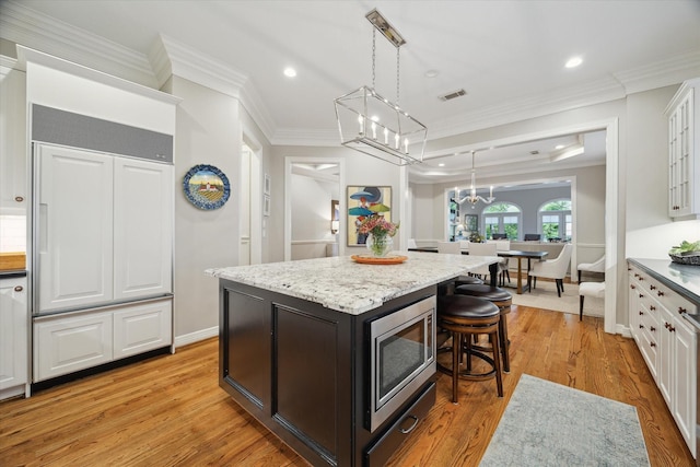 333 Sugarberry Cir, Houston, TX 77024 - kitchen with built in appliances, a breakfast bar, light wood-style flooring, ornamental molding, and a kitchen island