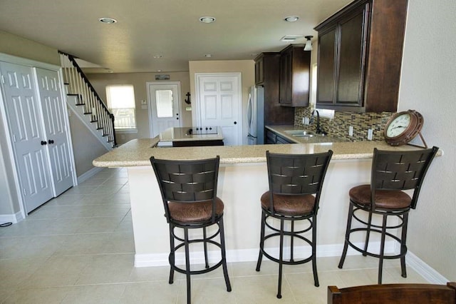 2028 County Road 201, Sargent, TX 77414 - kitchen with freestanding refrigerator, dark brown cabinetry, backsplash, light tile patterned floors, and recessed lighting