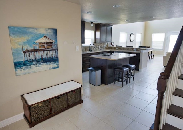 2028 County Road 201, Sargent, TX 77414 - kitchen featuring a peninsula, a breakfast bar, a kitchen island, backsplash, and light tile patterned flooring