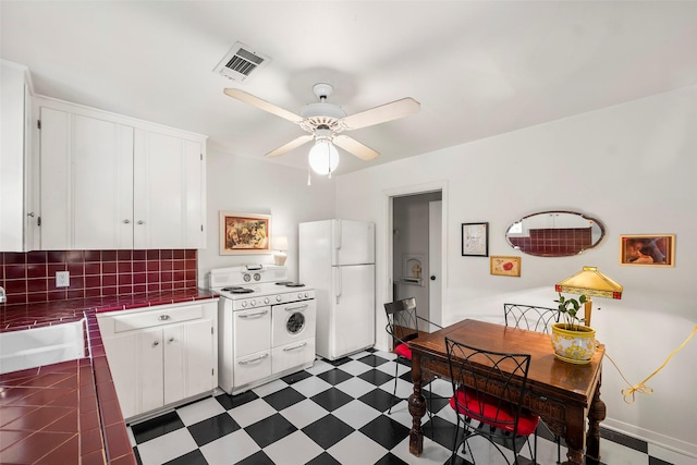 2114 Saxon Dr, Houston, TX 77018 - kitchen with white appliances, tile countertops, white cabinetry, ceiling fan, and backsplash