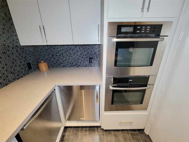 3124 Mid Ln, Houston, TX 77027 - kitchen with stainless steel double oven, backsplash, white cabinetry, and light countertops