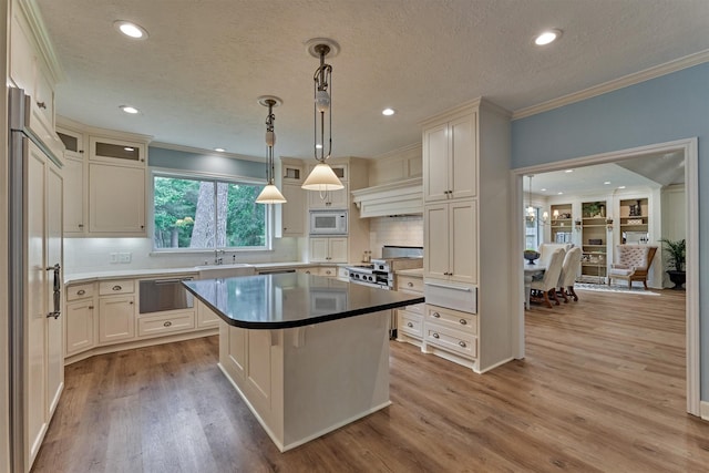 23119 Hampton Forest Ln, Spring, TX 77389 - kitchen with built in appliances, crown molding, recessed lighting, light wood-type flooring, and a center island