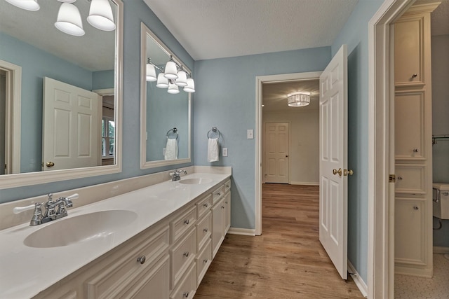 23119 Hampton Forest Ln, Spring, TX 77389 - bathroom featuring wood finished floors, double vanity, and a textured ceiling