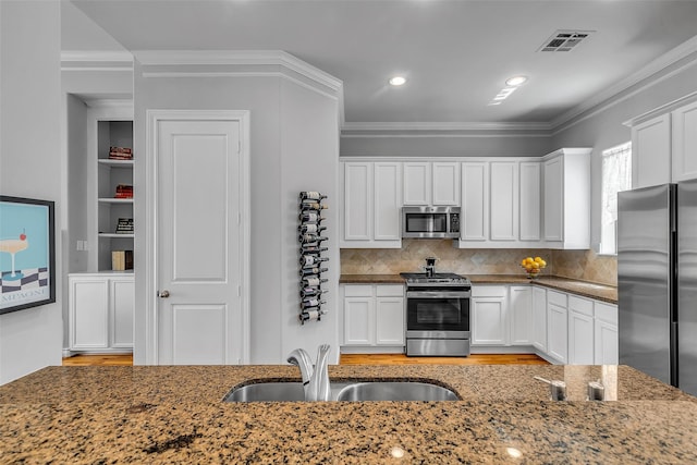 2206 Hilshire Glen Ct, Houston, TX 77080 - kitchen featuring stainless steel appliances, dark stone counters, white cabinets, ornamental molding, and recessed lighting