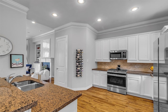 2206 Hilshire Glen Ct, Houston, TX 77080 - kitchen with appliances with stainless steel finishes, light wood-style flooring, white cabinets, decorative backsplash, and ornamental molding