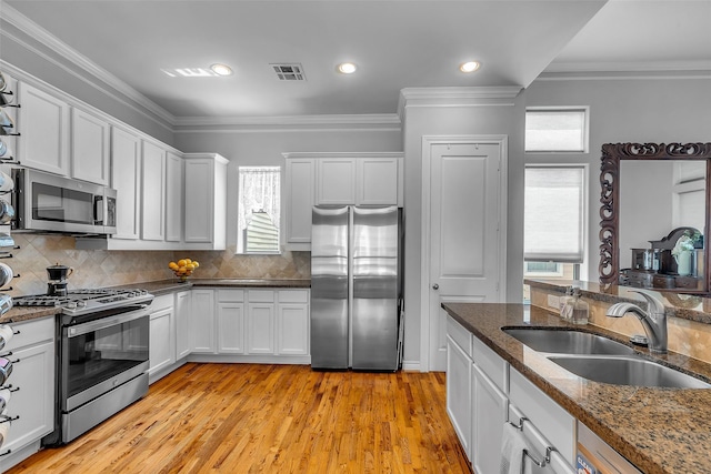 2206 Hilshire Glen Ct, Houston, TX 77080 - kitchen with appliances with stainless steel finishes, white cabinetry, crown molding, tasteful backsplash, and dark stone countertops