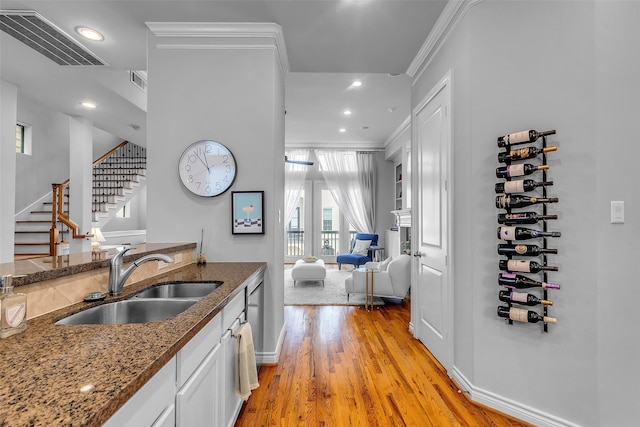 2206 Hilshire Glen Ct, Houston, TX 77080 - kitchen with ornamental molding, dark stone counters, light wood finished floors, white cabinetry, and recessed lighting