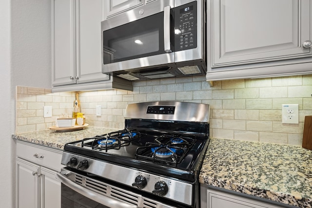 16863 Big Reed Dr, Humble, TX 77346 - kitchen featuring stainless steel appliances, backsplash, light stone counters, and white cabinetry