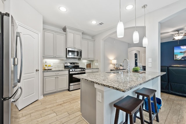 16863 Big Reed Dr, Humble, TX 77346 - kitchen featuring appliances with stainless steel finishes, arched walkways, light wood-style flooring, tasteful backsplash, and recessed lighting