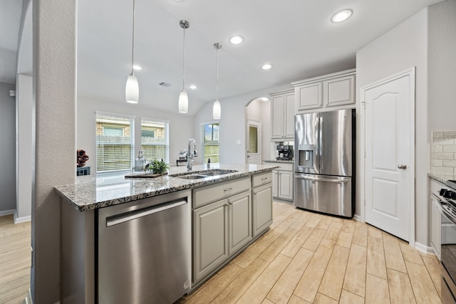 16863 Big Reed Dr, Humble, TX 77346 - kitchen with stainless steel appliances, arched walkways, light wood-style flooring, light stone countertops, and recessed lighting
