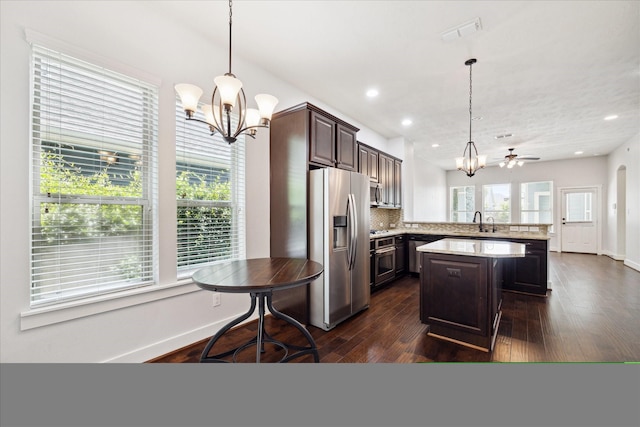 17011 Seminole Ridge Dr, Cypress, TX 77433 - kitchen with a chandelier, appliances with stainless steel finishes, dark brown cabinets, dark wood finished floors, and recessed lighting
