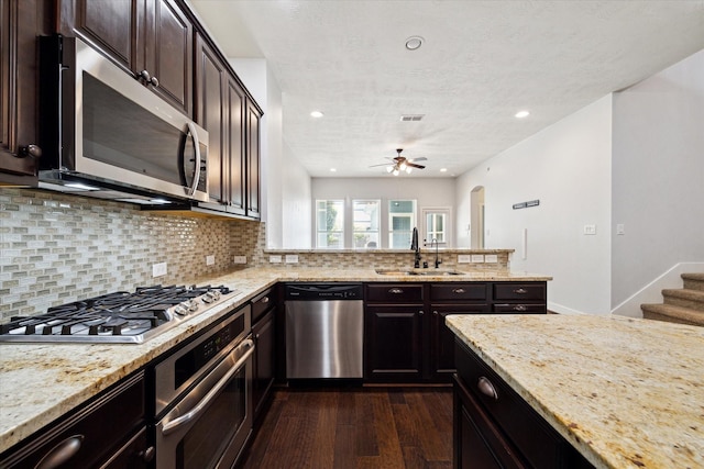 17011 Seminole Ridge Dr, Cypress, TX 77433 - kitchen with stainless steel appliances, dark wood finished floors, light stone counters, tasteful backsplash, and ceiling fan