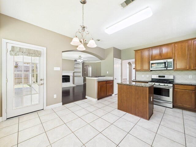 8122 Silver Lure Dr, Humble, TX 77346 - kitchen featuring stainless steel appliances, arched walkways, a kitchen island, decorative backsplash, and light tile patterned floors