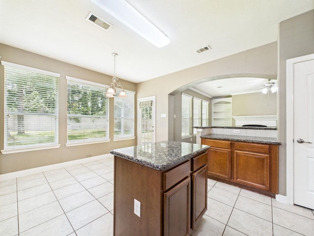 8122 Silver Lure Dr, Humble, TX 77346 - kitchen featuring arched walkways, a ceiling fan, light tile patterned flooring, a center island, and dark stone countertops