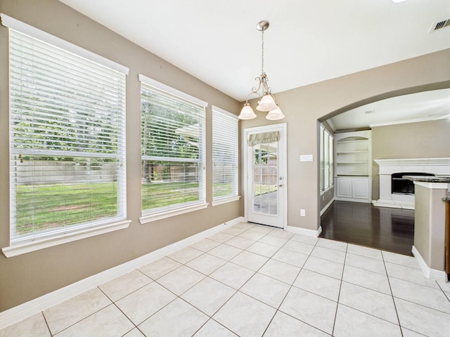 8122 Silver Lure Dr, Humble, TX 77346 - unfurnished dining area with light tile patterned floors, arched walkways, a fireplace with raised hearth, and a chandelier