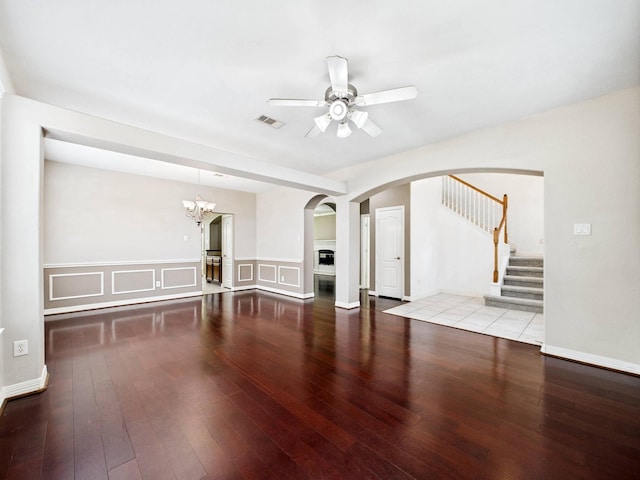 8122 Silver Lure Dr, Humble, TX 77346 - unfurnished living room featuring a ceiling fan, arched walkways, hardwood / wood-style flooring, a wainscoted wall, and stairway