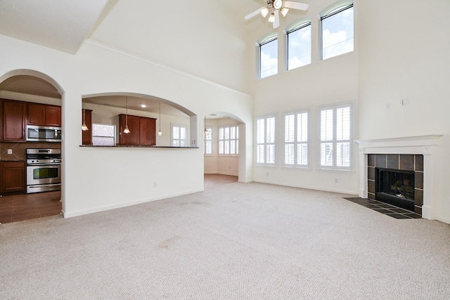 150 Nina Ln, Stafford, TX 77477 - unfurnished living room featuring carpet floors, a ceiling fan, a fireplace, and a towering ceiling