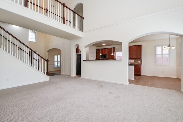 150 Nina Ln, Stafford, TX 77477 - unfurnished living room with light colored carpet, a chandelier, light tile patterned floors, a towering ceiling, and stairway