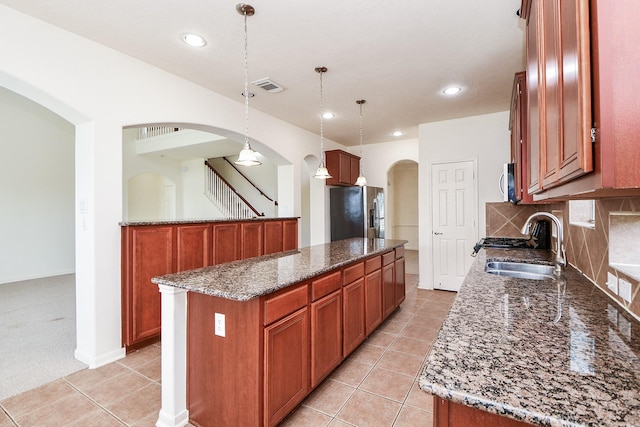 150 Nina Ln, Stafford, TX 77477 - kitchen with stainless steel appliances, a center island, arched walkways, light tile patterned floors, and recessed lighting