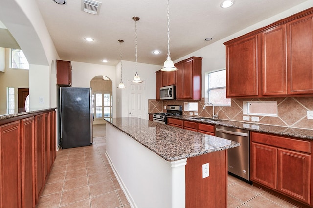 150 Nina Ln, Stafford, TX 77477 - kitchen featuring stainless steel appliances, arched walkways, a center island, tasteful backsplash, and dark stone countertops