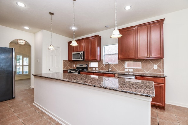 150 Nina Ln, Stafford, TX 77477 - kitchen featuring stainless steel appliances, arched walkways, plenty of natural light, light tile patterned floors, and recessed lighting