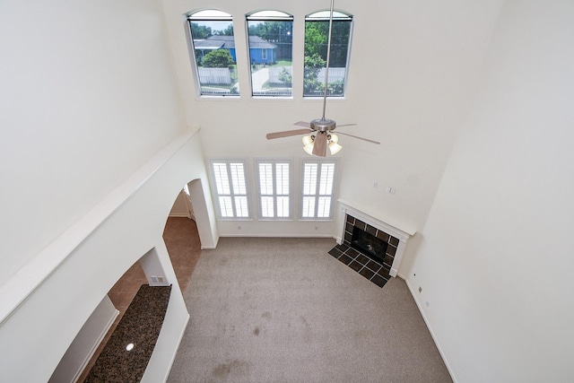 150 Nina Ln, Stafford, TX 77477 - unfurnished living room featuring a fireplace, ceiling fan, a towering ceiling, carpet, and arched walkways