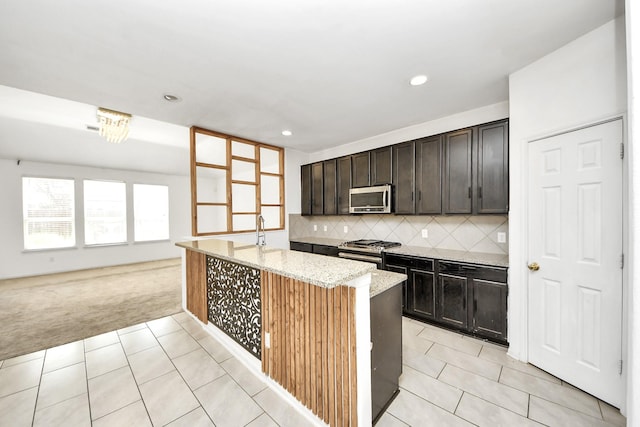 3619 Barkers Run Dr, Houston, TX 77084 - kitchen with stainless steel appliances, light carpet, light stone counters, an island with sink, and light tile patterned floors