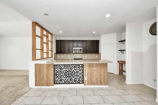 3619 Barkers Run Dr, Houston, TX 77084 - kitchen featuring stainless steel microwave, tasteful backsplash, recessed lighting, light tile patterned flooring, and light stone countertops