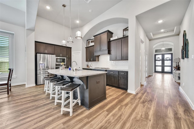 4327 Sage Glen Ln, Fulshear, TX 77441 - kitchen with appliances with stainless steel finishes, light wood-type flooring, dark brown cabinets, a breakfast bar area, and healthy amount of natural light