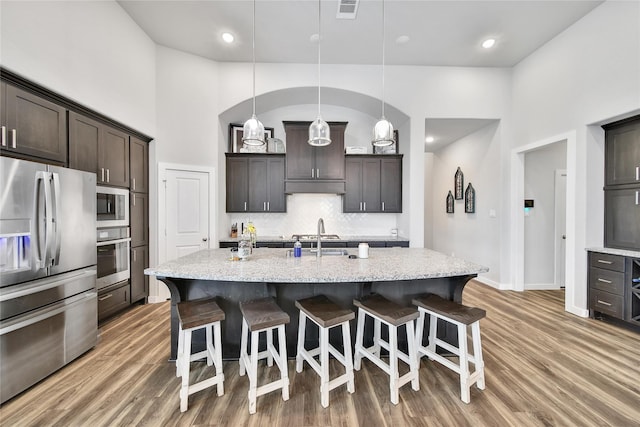 4327 Sage Glen Ln, Fulshear, TX 77441 - kitchen featuring stainless steel appliances, under cabinet range hood, decorative backsplash, a breakfast bar, and a towering ceiling