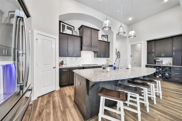 4327 Sage Glen Ln, Fulshear, TX 77441 - kitchen with appliances with stainless steel finishes, light wood-type flooring, tasteful backsplash, light stone countertops, and a breakfast bar