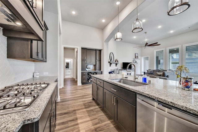 4327 Sage Glen Ln, Fulshear, TX 77441 - kitchen with stainless steel appliances, light wood finished floors, a ceiling fan, custom exhaust hood, and dark brown cabinetry