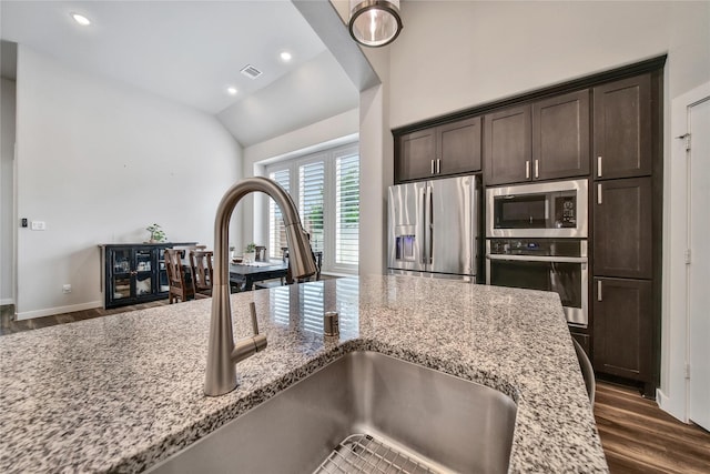 4327 Sage Glen Ln, Fulshear, TX 77441 - kitchen featuring stainless steel appliances, dark brown cabinets, dark wood-type flooring, light stone countertops, and vaulted ceiling