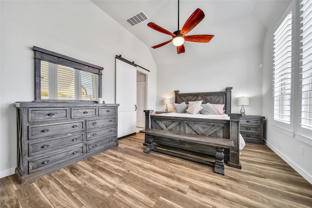 4327 Sage Glen Ln, Fulshear, TX 77441 - bedroom featuring a barn door, wood finished floors, multiple windows, high vaulted ceiling, and ceiling fan