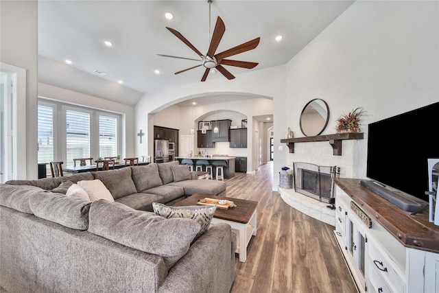 4327 Sage Glen Ln, Fulshear, TX 77441 - living area with ceiling fan, arched walkways, wood finished floors, lofted ceiling, and a stone fireplace