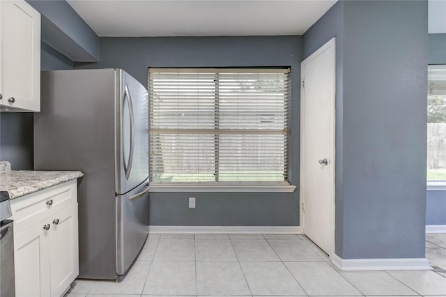 2710 Magnolia Ct, Stafford, TX 77477 - kitchen with freestanding refrigerator, white cabinetry, light tile patterned flooring, and light stone countertops