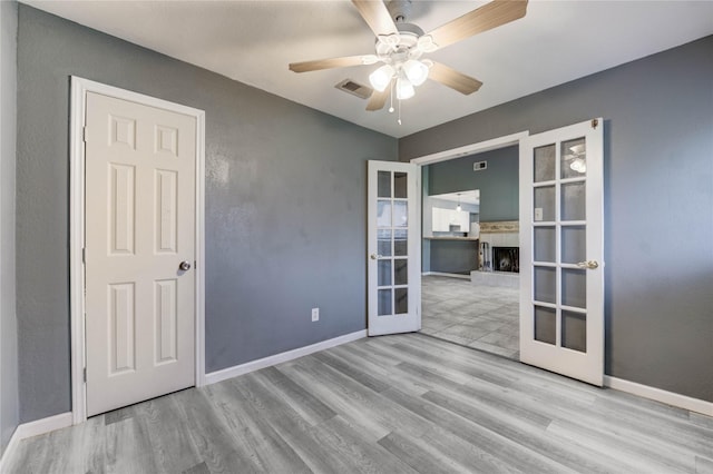 2710 Magnolia Ct, Stafford, TX 77477 - empty room with french doors, wood finished floors, a fireplace with raised hearth, and a ceiling fan