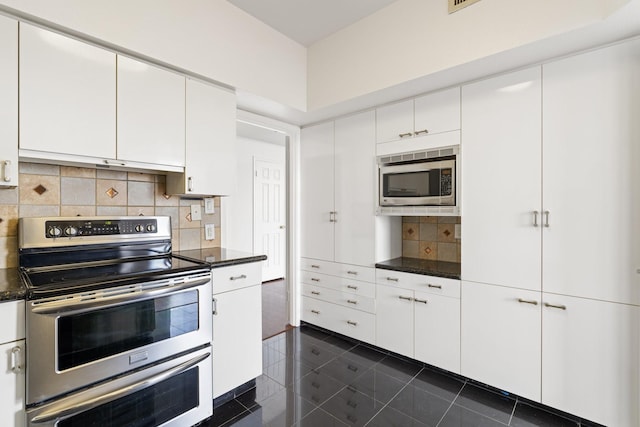 15 Greenway Plz Unit 10G, Houston, TX 77046 - kitchen with appliances with stainless steel finishes, dark countertops, tasteful backsplash, white cabinetry, and dark tile patterned flooring