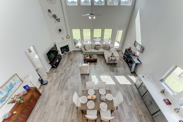 6907 Pondhawk Dr, Katy, TX 77493 - living room featuring plenty of natural light, a high ceiling, a ceiling fan, light wood finished floors, and a fireplace