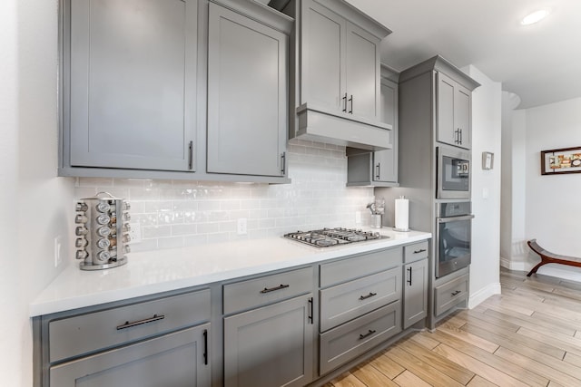 6907 Pondhawk Dr, Katy, TX 77493 - kitchen with stainless steel appliances, gray cabinetry, tasteful backsplash, and under cabinet range hood