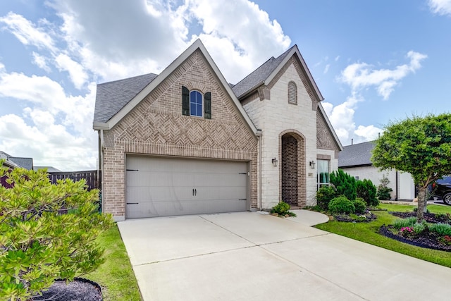 6907 Pondhawk Dr, Katy, TX 77493 - french country inspired facade featuring brick siding, driveway, roof with shingles, and an attached garage
