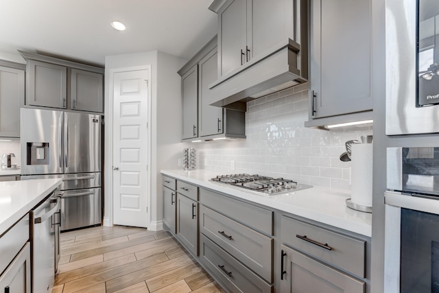 6907 Pondhawk Dr, Katy, TX 77493 - kitchen featuring appliances with stainless steel finishes, gray cabinets, light countertops, backsplash, and light wood-style floors