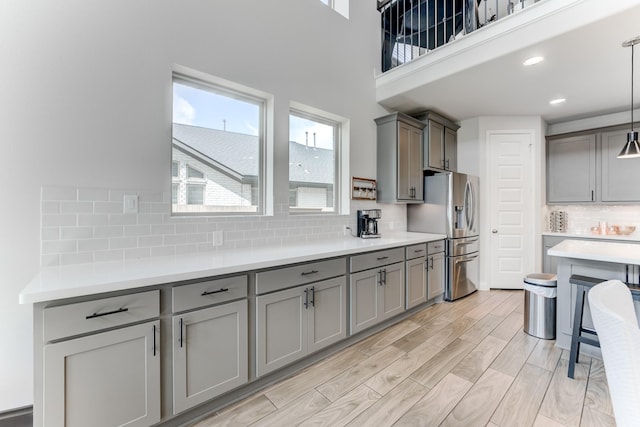 6907 Pondhawk Dr, Katy, TX 77493 - kitchen with gray cabinetry, stainless steel refrigerator with ice dispenser, tasteful backsplash, light countertops, and a towering ceiling