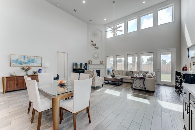 6907 Pondhawk Dr, Katy, TX 77493 - dining space with ceiling fan, a towering ceiling, recessed lighting, light wood-style floors, and a fireplace