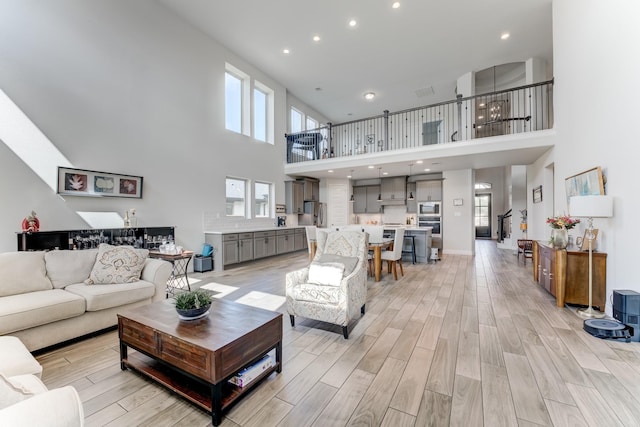 6907 Pondhawk Dr, Katy, TX 77493 - living room featuring a towering ceiling, light wood-style flooring, and recessed lighting