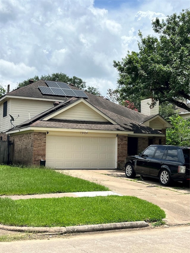 7502 Grackle Dr, Cypress, TX 77433 - view of front of house with brick siding, a garage, concrete driveway, roof mounted solar panels, and roof with shingles