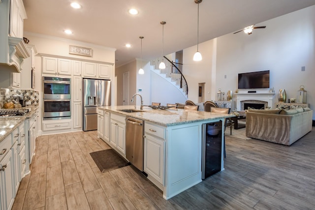 9411 Plaza Point Dr, Missouri City, TX 77459 - kitchen with stainless steel appliances, open floor plan, light wood-style floors, white cabinetry, and light stone counters