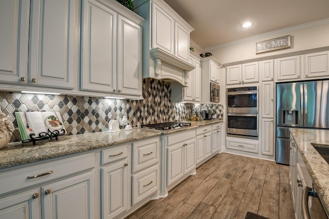 9411 Plaza Point Dr, Missouri City, TX 77459 - kitchen with stainless steel appliances, crown molding, backsplash, light wood-type flooring, and light stone countertops