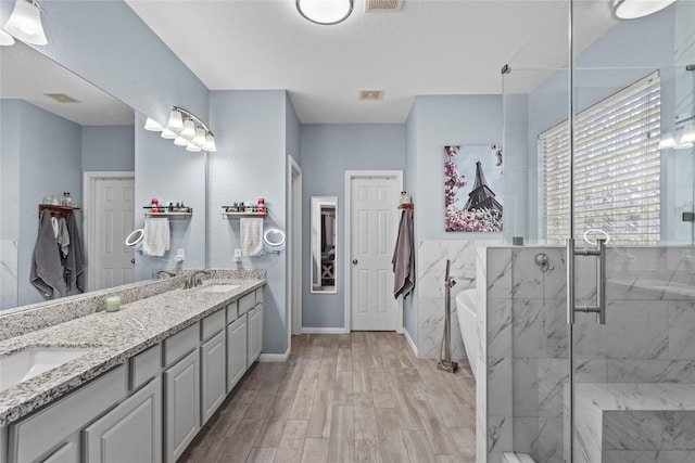 1011 Elm Pointe, League City, TX 77573 - bathroom featuring a soaking tub, double vanity, a marble finish shower, and wood finished floors